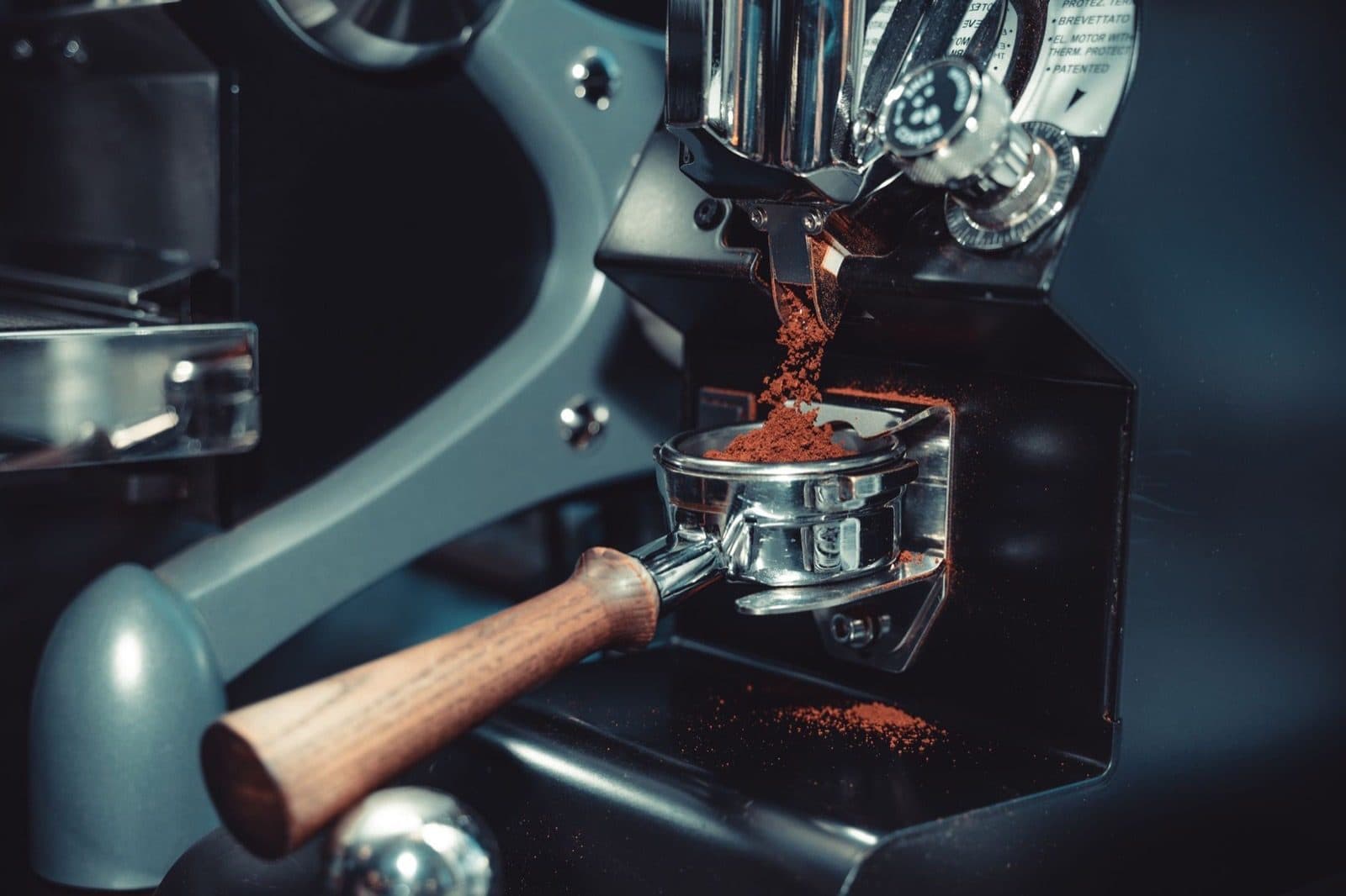 Ground coffee falling into a portafilter from a grinder.