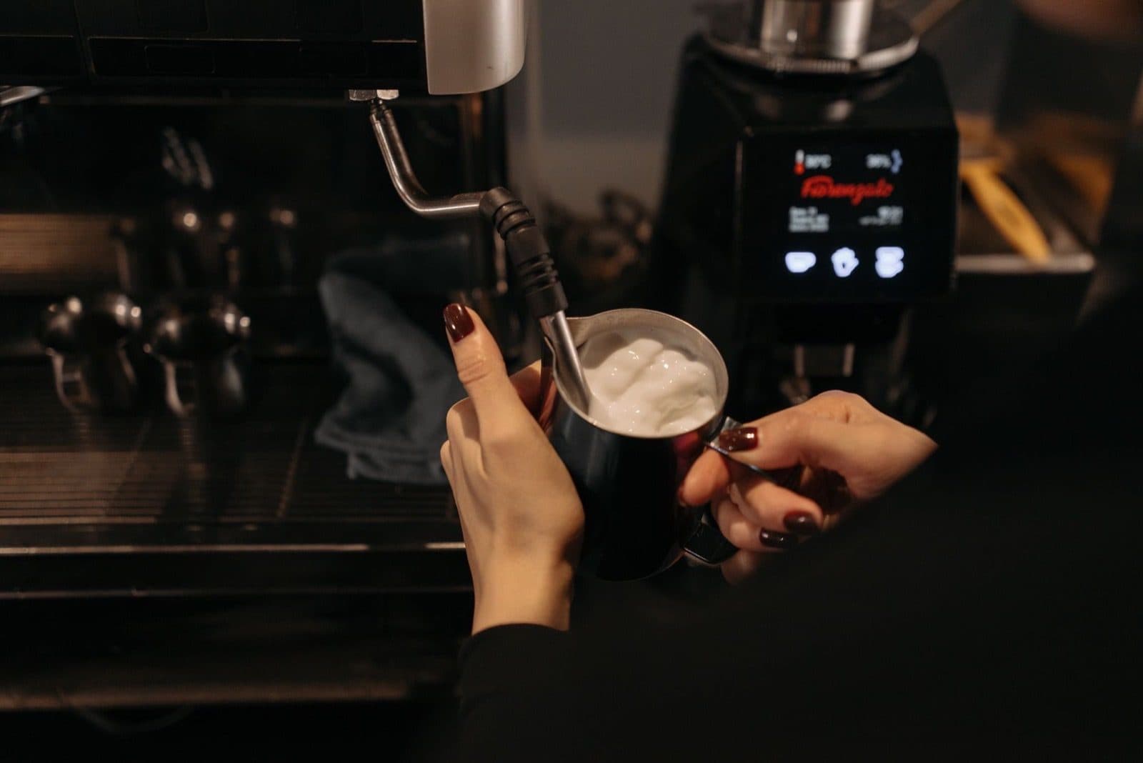 Barista using an espresso-machine steam wand.