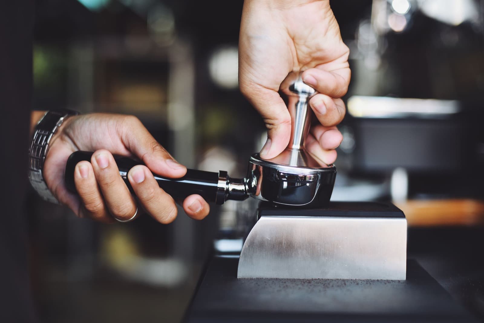 Barista preparing espresso with a portafilter at the machine.