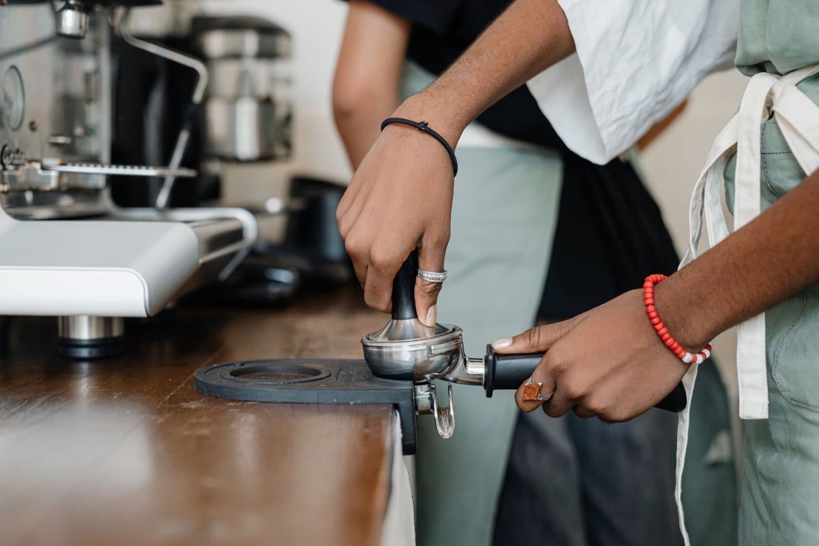 Barista dosing ground coffee into a portafilter at an espresso machine.