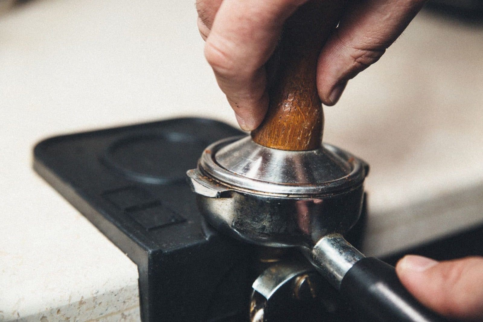 Hands using a portafilter while preparing espresso.